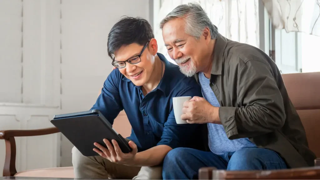 Middle aged dad looking at computer with son.