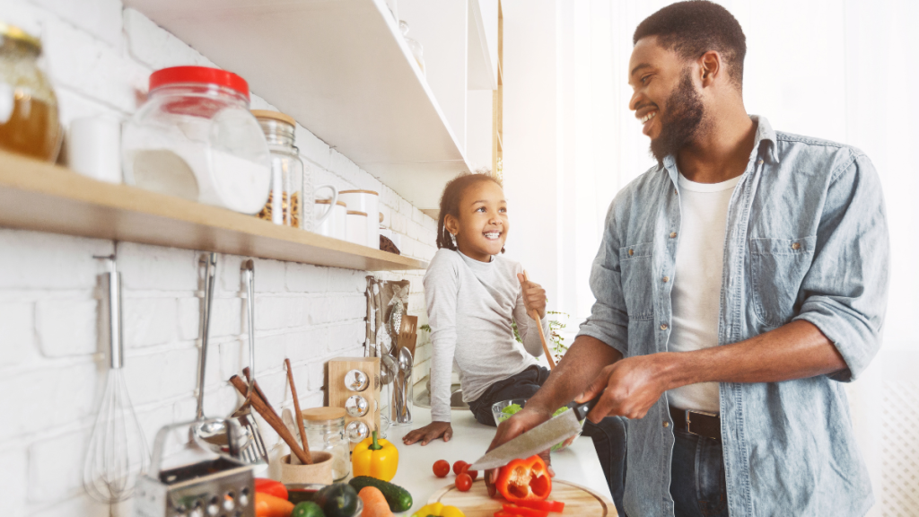 Dad cutting vegetables with daughter.