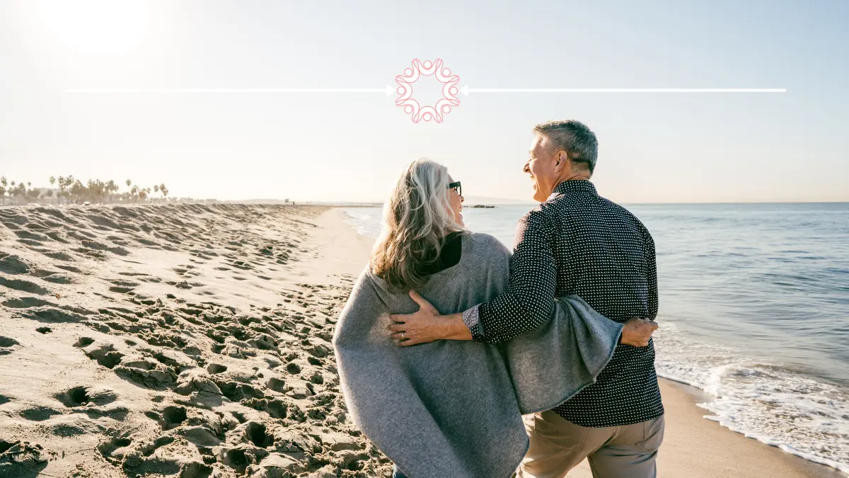 Older couple with their arms around each other at the beach.